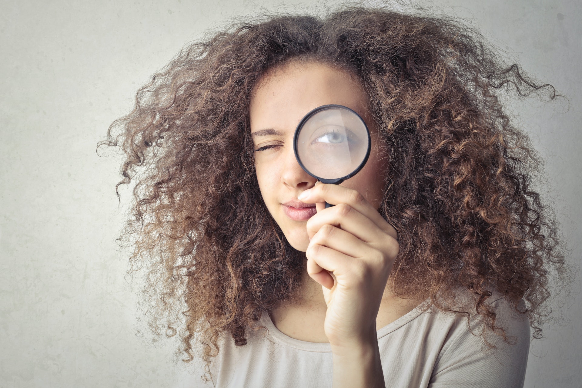 Girl holding a magnifying glass to her eye